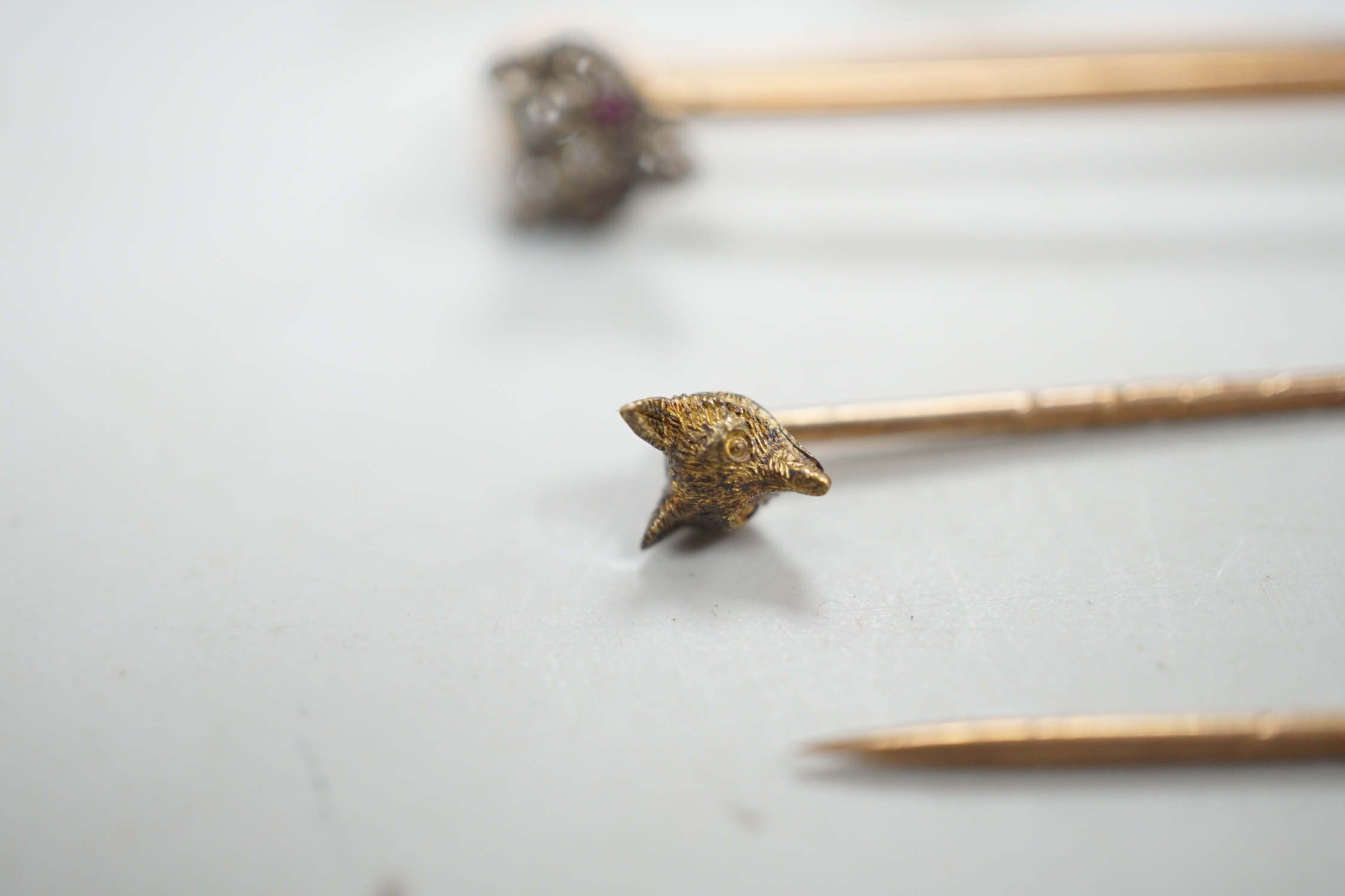A Victorian yellow metal and diamond cluster set fox head pin, 44mm, two other fox head pins and a 15ct fox head and hunting horn brooch, gross weight 8.5 grams.